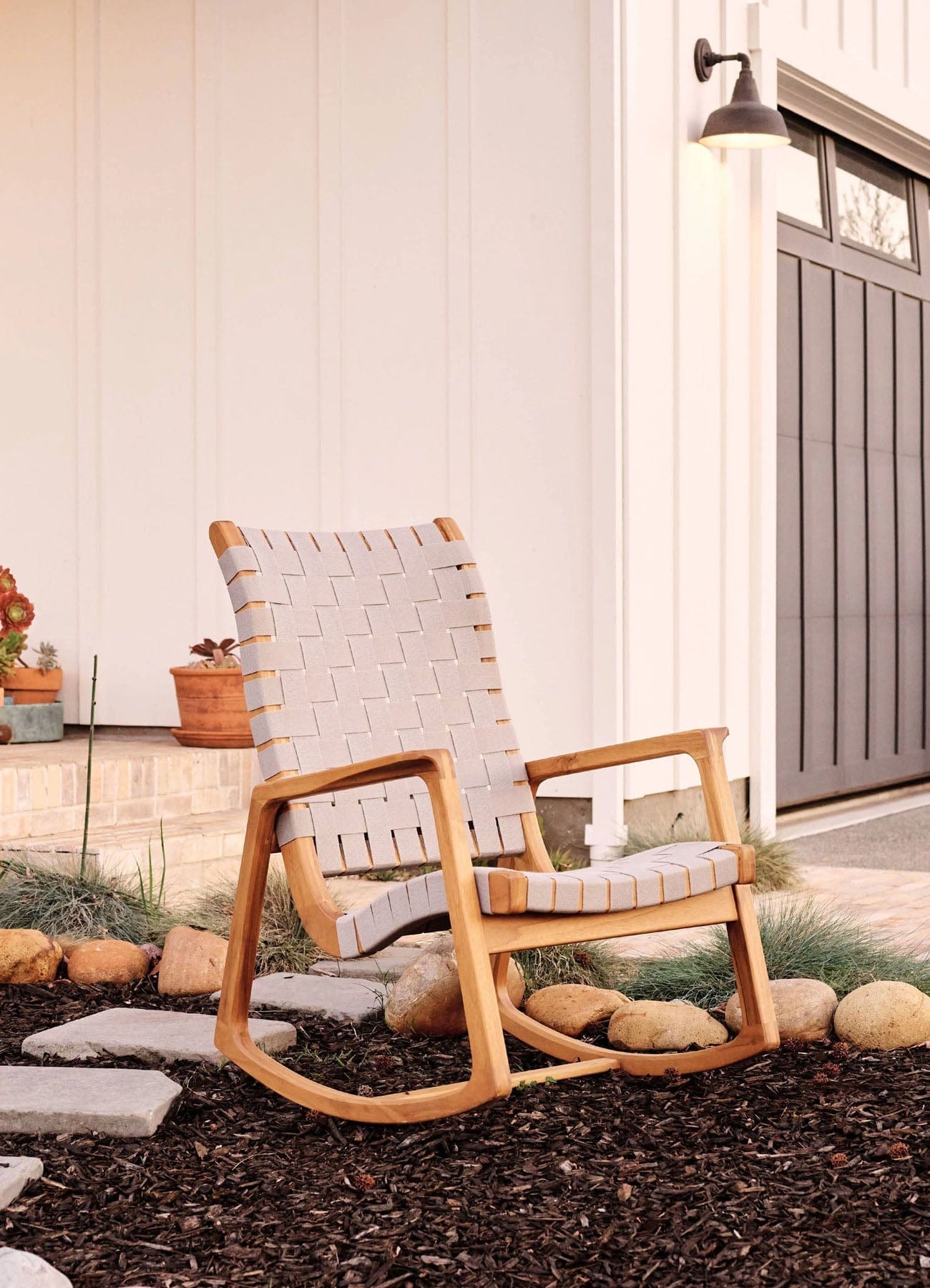 Wooden teak rocking chair with woven backrest on a patio