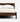 A close-up of a modern wooden bed frame with a woven cane headboard, dressed in white bedding and pillows, set against a clean white background.