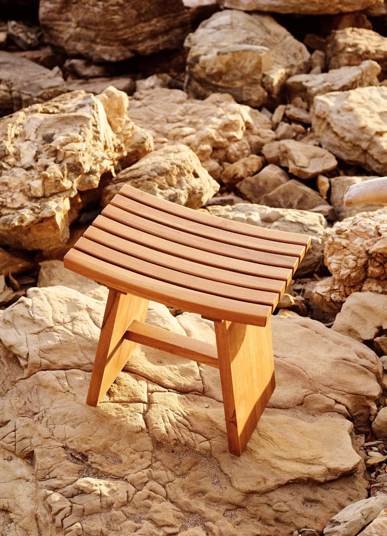 Solid teak wooden stool on a rocky surface